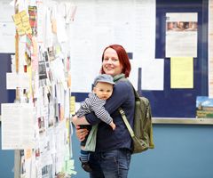 Das Bild zeigt eine Studentin mit Kind auf dem Arm.