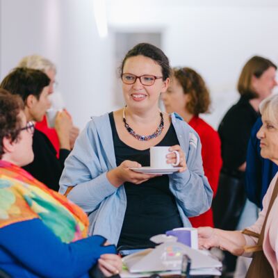 Neun Frauen stehend und im Dialog bei der Kaffeepause.