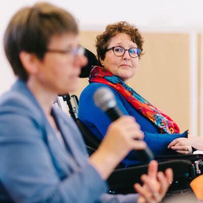 Karen Schallert blickt zu Beate Gilles, die gerade ins Mikro spricht.