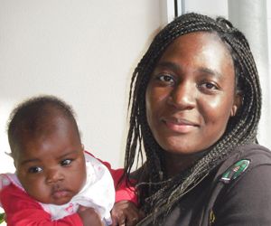 Das Bild zeigt eine junge Frau mit Baby auf dem Arm.