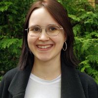 Lena Lang Lena Lang, lächelnd mit schulterlangem Haar und Brille