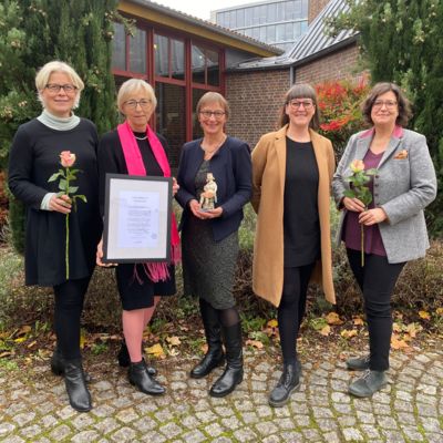 Fünf Frauen mit Preis, Urkunde und zwei Rosen in der Hand stehen vor dem Maternushaus und lächeln.