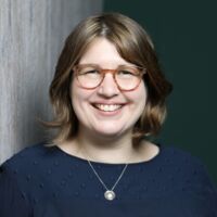 Andrea Heim mit kinnlangem brauen Haar und einer Brille lächelt in die Kamera.