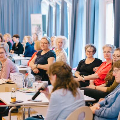 Viele Frauen sitzen bei der Abschlussrunde und hören zu.