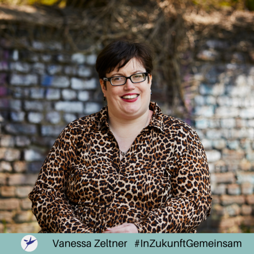 Das Bild zeigt Vanessa Zeltner, die in die Kamera lächelt. Sie trägt eine Bluse mit Leopardenmuster und eine Brille. Sie hat kurzes Schwarzes Haar und trägt einen roten Lippenstift