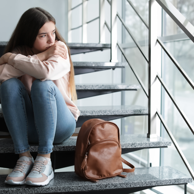 Junge Frau, die auf einer Treppe sitzt und traurig nach draußen schaut