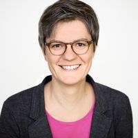 Stephanie Feder mit kurzen braungrauen Haaren und brauner Brille, lächelt in die Kamera.