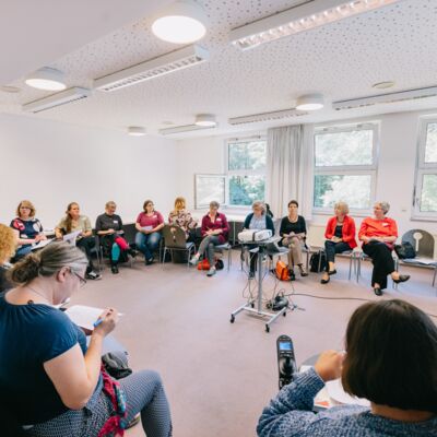 17 Frauen in einem großen Stuhlkreis.